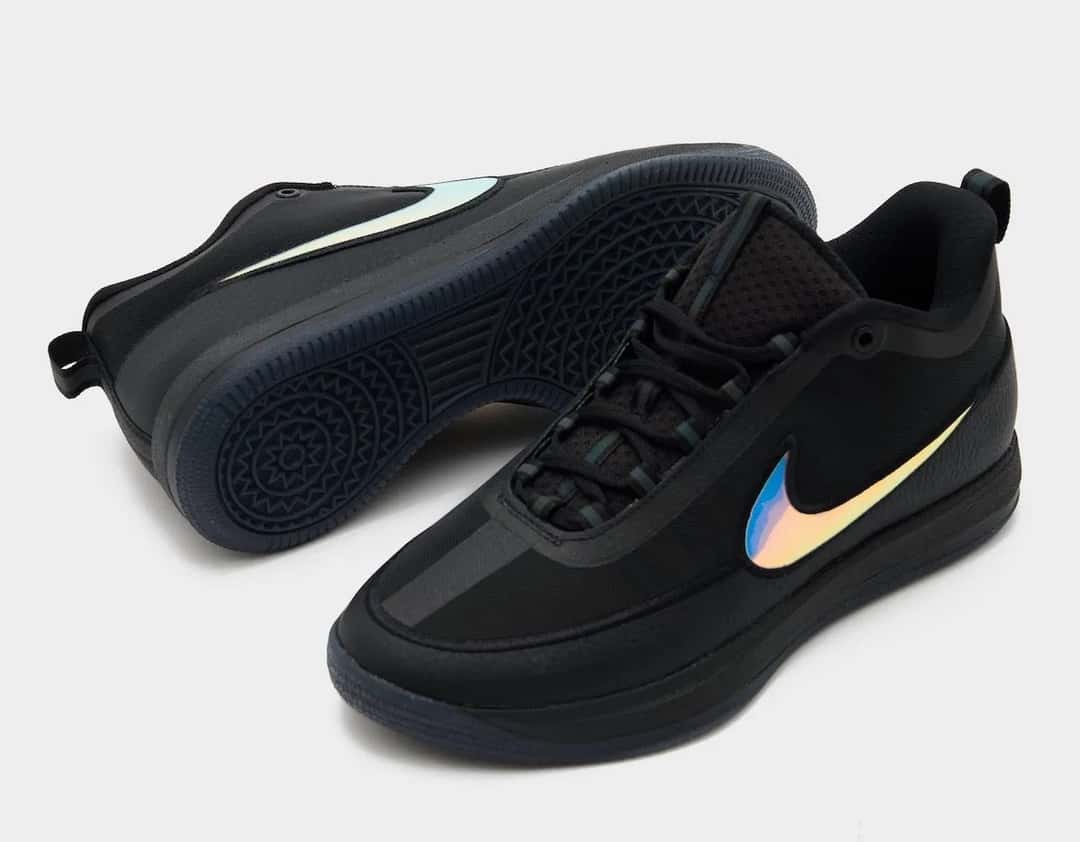 Nike Book 2 Desert Night visto desde abajo, con la suela translúcida oscura y la capellada negra con el Swoosh iridiscente