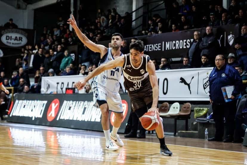 Mauro Cosolito, de Platense, con la camiseta marrón número 30, avanza con la pelota ante la marca de Agustín Brocal, de Oberá, con la camiseta blanca número 11, en el Microestadio Ciudad de Vicente López