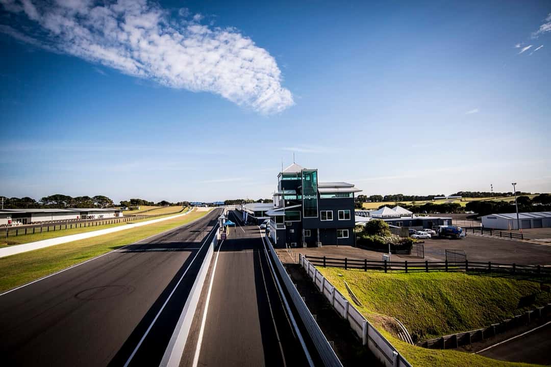 Foto de archivo: la recta principal de Phillip Island vacía, con la torre de control a la derecha y el cielo azul con una nube larga