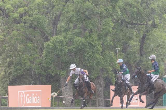 Un jugador de La Natividad La Dolfina, de blanco, le pega a la bocha bajo la lluvia ante dos rivales de La Ensenada en la cancha de Tortuguitas