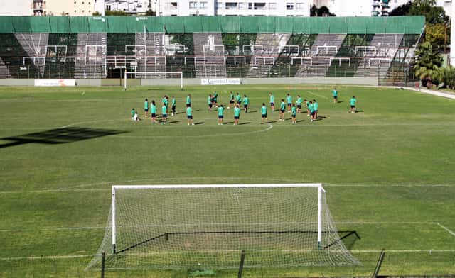 La tribuna local del estadio de Ferro, de color verde, con jugadores entrenando en la cancha; foto de archivo de 2012 (foto: Facundo Diez, Wikimedia Commons, licencia CC BY-SA 3.0)