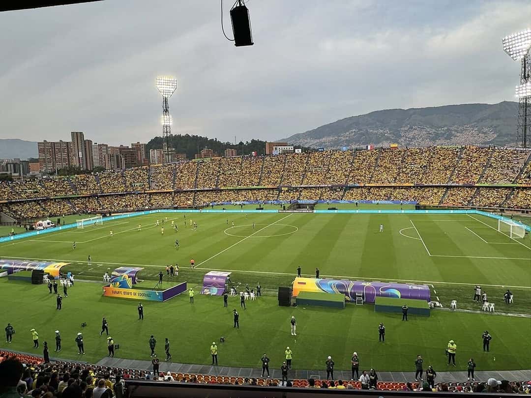 El estadio Atanasio Girardot con las tribunas llenas de hinchas vestidos de amarillo durante un partido en una tarde nublada, con los cerros de Medellín de fondo; foto de archivo de octubre de 2024 (foto: Oo. Denis .oO, Wikimedia Commons, licencia CC BY 4.0)