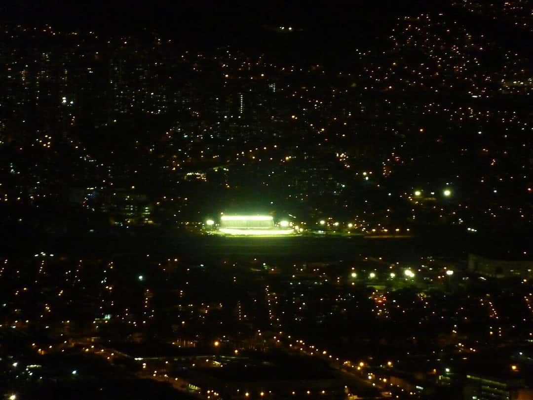 Vista nocturna de Medellín desde un cerro, con las luces de la ciudad y el estadio Atanasio Girardot iluminado en el centro; foto de archivo de 2013 (foto: Harrysaurio, Wikimedia Commons, licencia CC BY-SA 3.0)