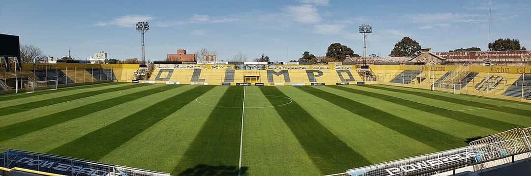 El estadio Roberto Natalio Carminatti, de Olimpo, en Bahía Blanca, con la cancha rayada y la tribuna amarilla y negra con el nombre del club; foto de archivo de diciembre de 2021 (foto: Club Olimpo, Wikimedia Commons, licencia CC BY-SA 4.0)