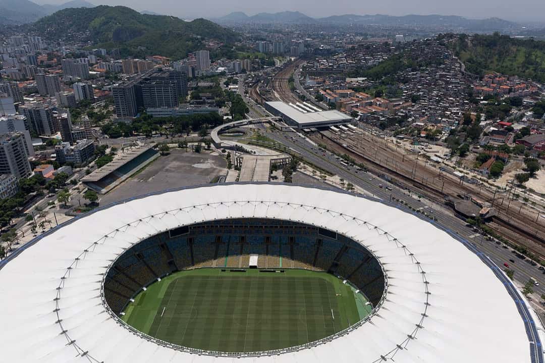 Vista aérea del estadio Maracaná de Río de Janeiro, con su techo blanco alrededor de las tribunas y el campo de juego, y la ciudad y los cerros de fondo; foto de archivo de diciembre de 2016 (foto: Diego Baravelli, Wikimedia Commons, licencia CC BY-SA 4.0)
