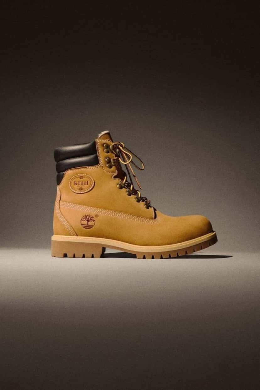 Kith x Timberland 6-Inch Shearling 40 Below Wheat sobre fondo oscuro, con el nobuk color trigo, el cuello negro acolchado y el logo ovalado de Kith