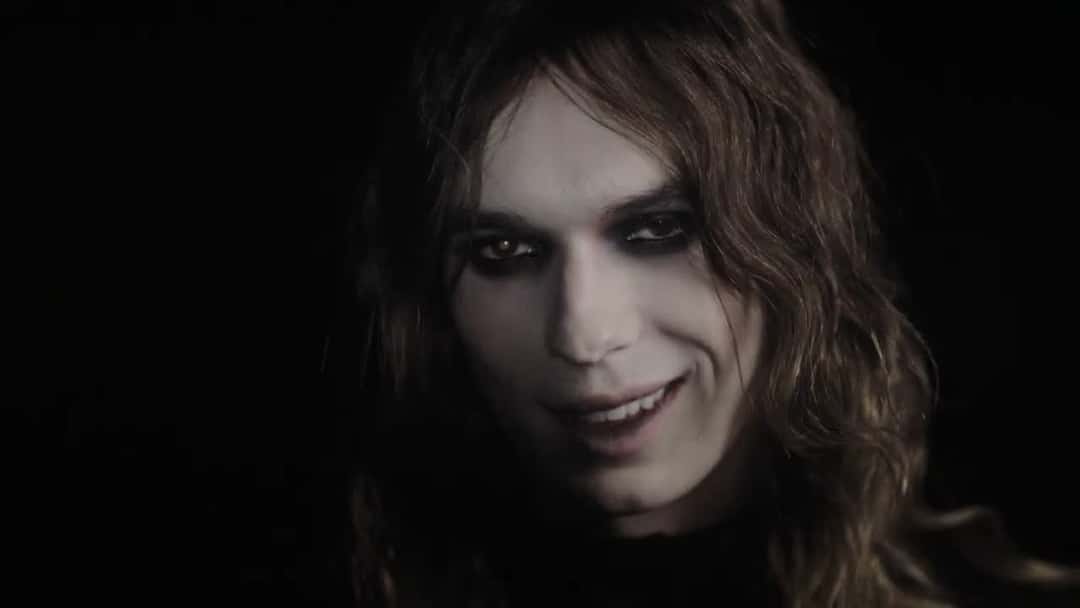 Fotograma del video oficial de «Hurt»: primer plano de 2hollis con el pelo largo castaño, los ojos delineados de negro y la cara pálida, sobre un fondo oscuro (foto de archivo)