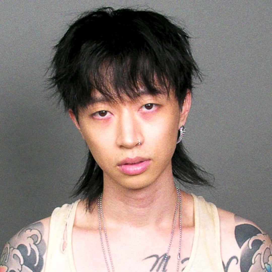 Portada del single «WANTCHU», de keshi: retrato del cantante, de pelo negro con flequillo, musculosa clara, cadenas y brazos tatuados, sobre fondo gris