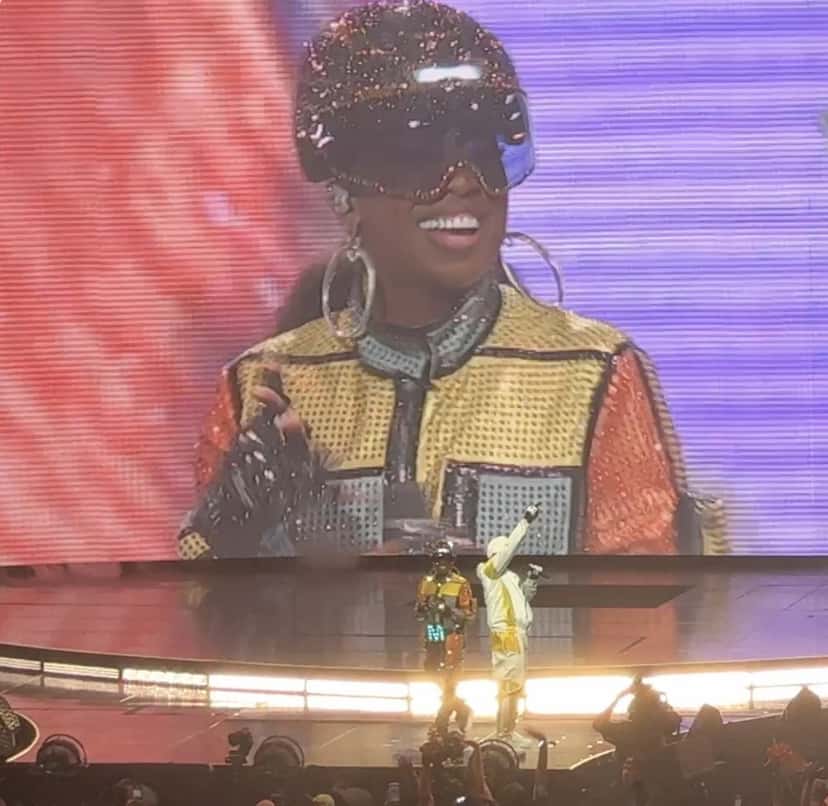 Missy Elliott sonríe en la pantalla gigante, con casco brillante y anteojos espejados, mientras canta en el escenario de su gira Out of This World en Chicago, en 2024 (foto de archivo). Foto: WOWyerrr, CC0, vía Wikimedia Commons