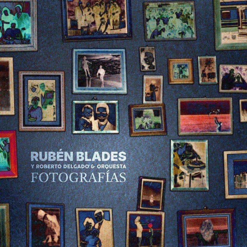 Portada de «Fotografías», de Rubén Blades con Roberto Delgado y Orquesta: una pared azul llena de cuadros y fotos enmarcadas de distintos tamaños, con el título en letras blancas