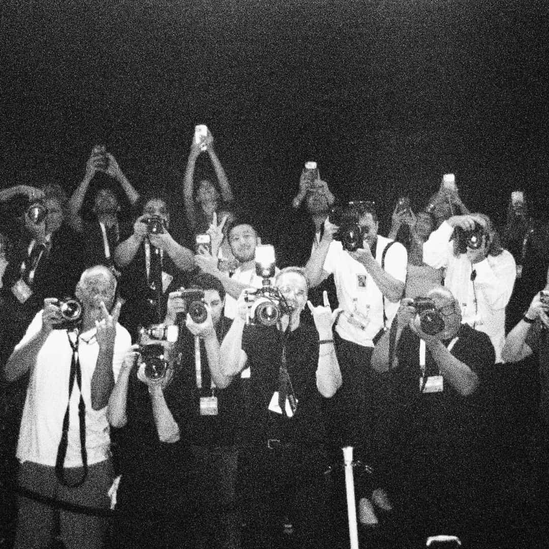 Portada de «Great Expectation (Live from the 2026 VMAs)», de Sienna Spiro: foto en blanco y negro de un grupo de fotógrafos que apuntan sus cámaras hacia el frente