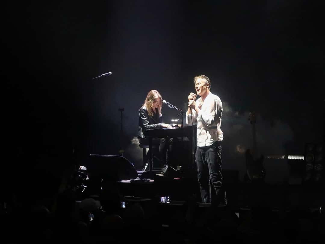 Brett Anderson canta parado junto al tecladista Neil Codling, sentado frente a un teclado, en un momento acústico de un show de Suede con el escenario casi a oscuras, en el Royal Festival Hall de Londres en 2025 (foto de archivo). Foto: Bex Walton, CC BY 4.0, vía Wikimedia Commons