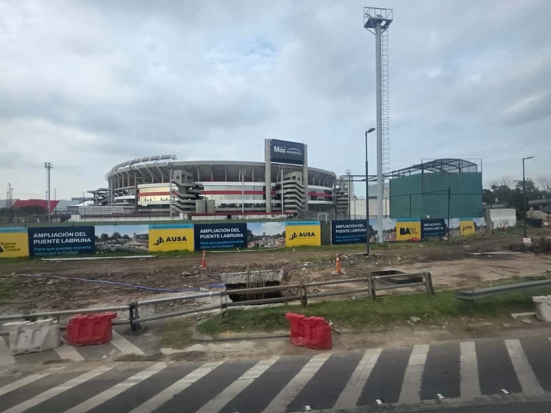 El Estadio River Plate visto desde la avenida Leopoldo Lugones, en Buenos Aires, en diciembre de 2025, con obras viales y vallas en primer plano (imagen del lugar del show). Foto: Horacio Cambeiro, CC BY 3.0, vía Wikimedia Commons