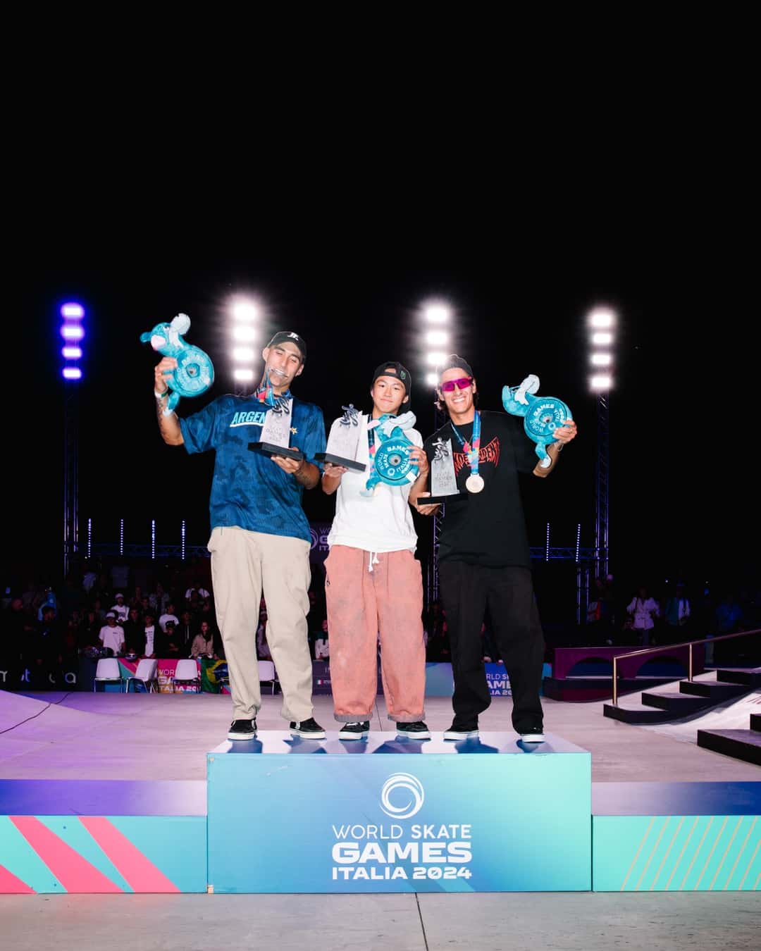 Matías Dell Olio con la camiseta de Argentina en el podio de street de los World Skate Games Italia 2024, junto a Toa Sasaki y Jhancarlos González