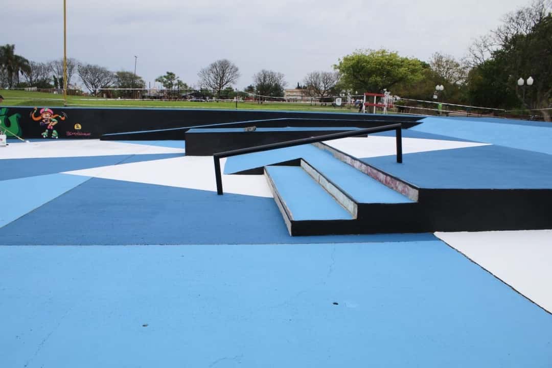 Escalones y barandas negras sobre el piso pintado en azul, celeste y blanco del skatepark de Gualeguaychú