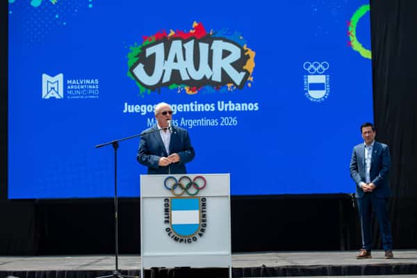 Mario Moccia habla en un atril del Comité Olímpico Argentino frente a una pantalla con el logo de los Juegos Argentinos Urbanos, en la ceremonia de apertura
