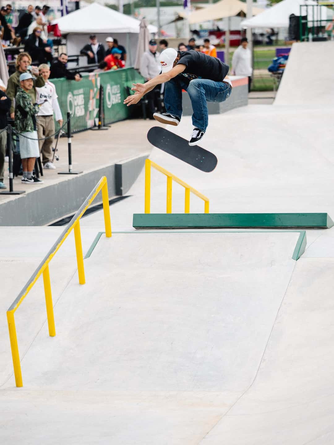 Jagger Eaton vuela con la tabla girando debajo de sus pies sobre la pista de street del Parque Olímpico de Luque, con público detrás de las vallas