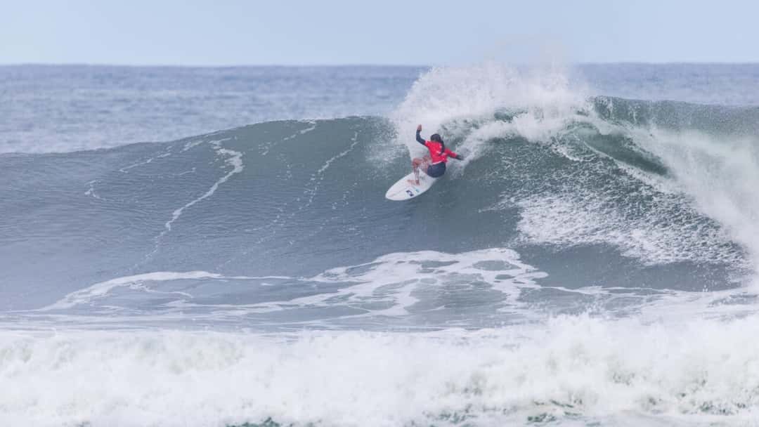 Kiara Goold, con lycra roja, gira de frente en la cresta de una ola de Sunset Beach, el martes 27 de octubre