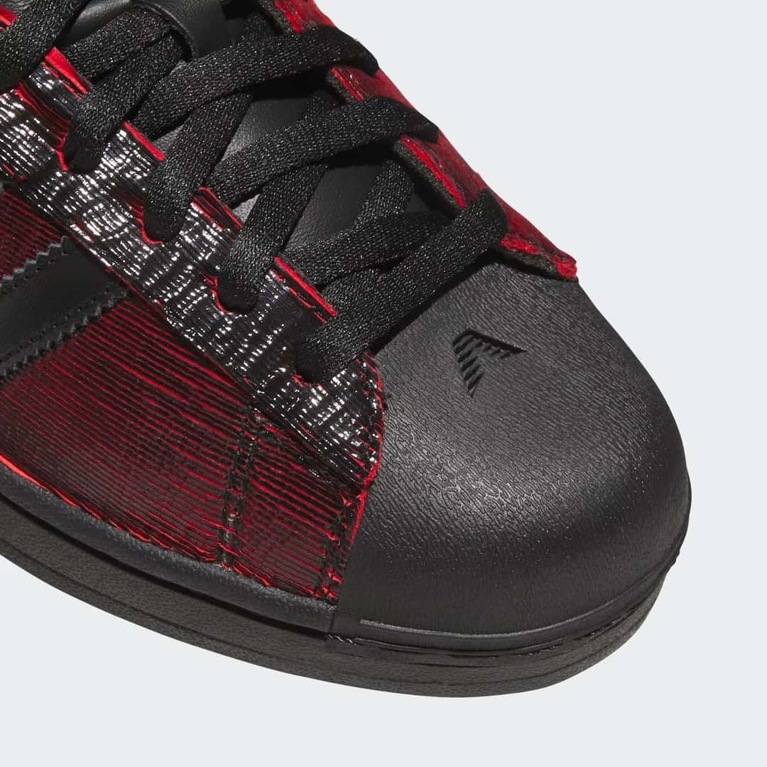 Primer plano de la puntera de la adidas Superstar Halloween de Anthony Edwards, de goma negra lisa con el logo AE y la capellada rayada en negro y rojo