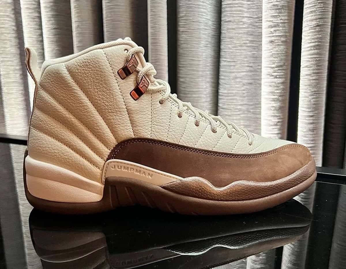 Air Jordan 12 Fireside de perfil con upper de cuero crema, mudguard marrón y ojales metálicos cobrizos