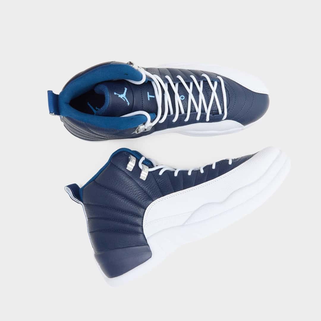 Par de Air Jordan 12 Obsidian visto desde arriba sobre fondo blanco, con cordones blancos, ganchos plateados, forro azul francés y el Jumpman celeste en la plantilla