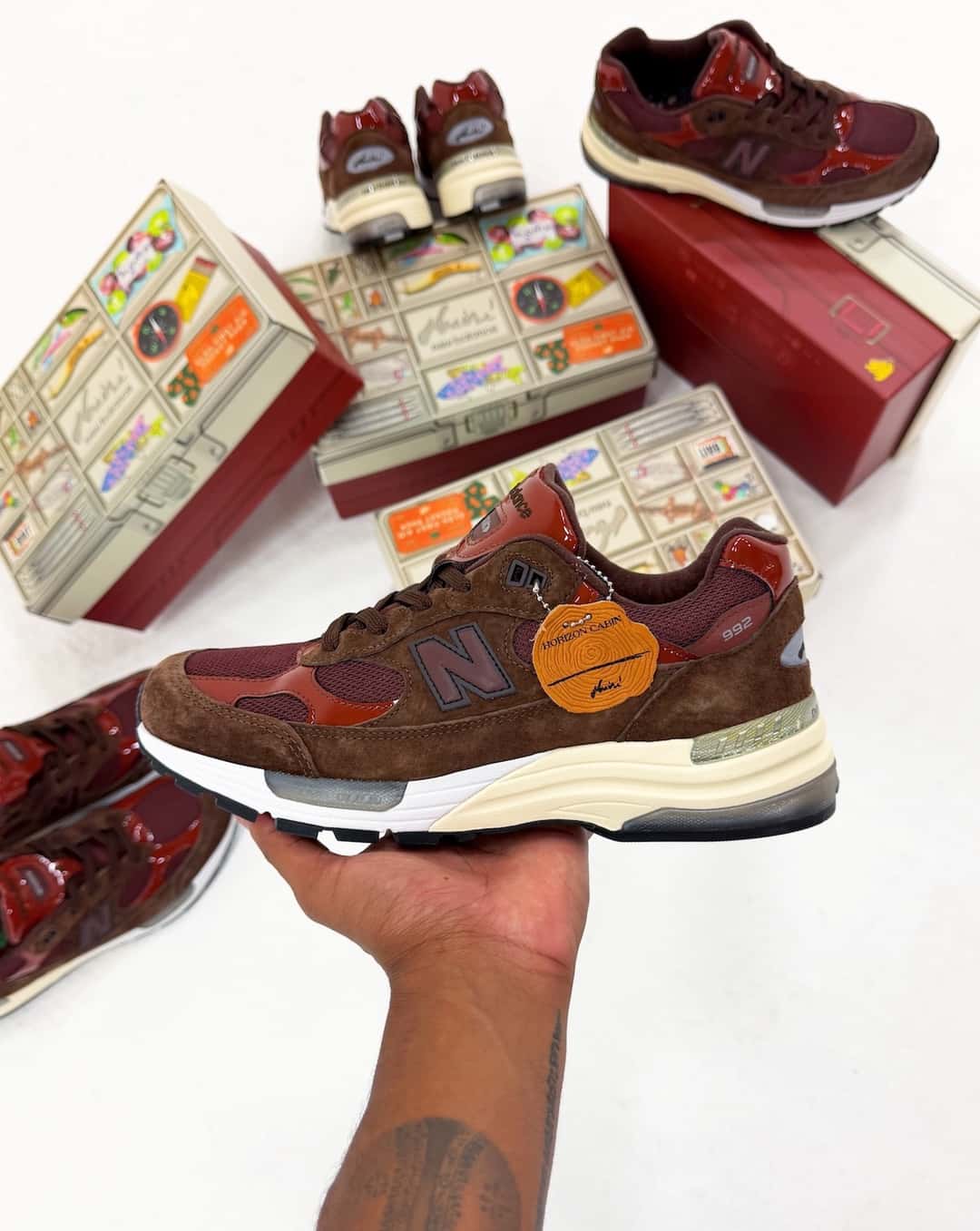 Aminé x New Balance 992 con el hangtag Horizon Cabin junto a las cajas inspiradas en una caja de pesca