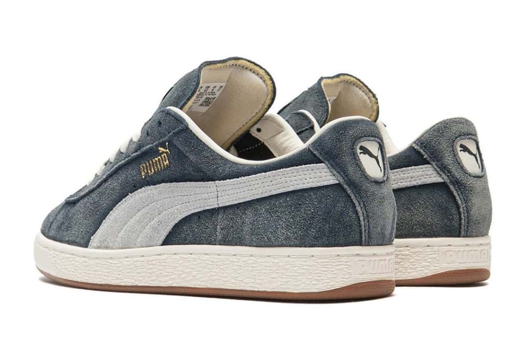 Par de A$AP Rocky x PUMA Suede '94 Faded Blue visto de atrás y de costado sobre fondo blanco, con el talón de gamuza azul, el logo del felino de PUMA y el forro color crema