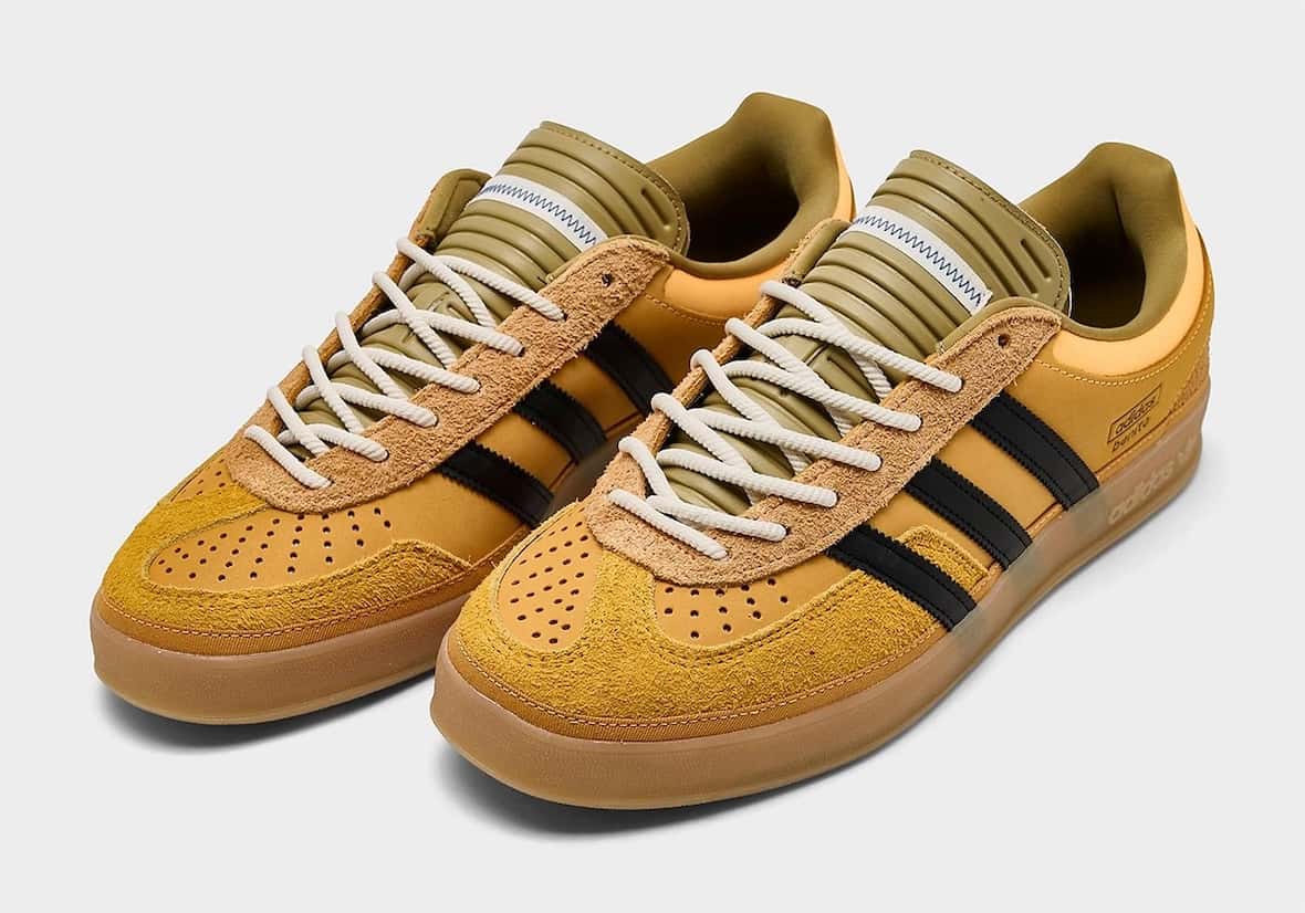Par de Bad Bunny x adidas Gazelle Indoor Solar Gold en amarillo dorado con tres tiras negras, lengüeta verde oliva acolchada, cordones de cuerda crema y suela gum