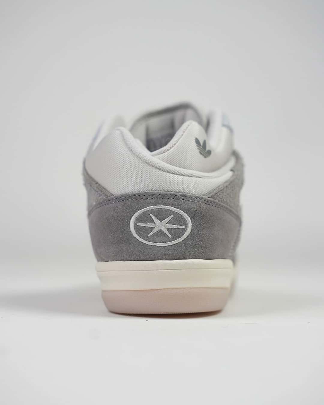 Talón de la adidas BadBo 1.0 Grey Three, con el logo circular grabado sobre la gamuza gris y la entresuela blanca