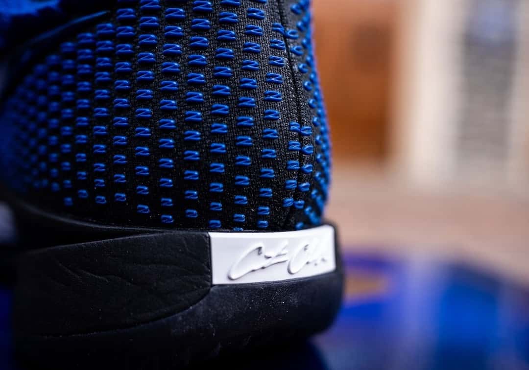 Detalle del talón de la Nike Caitlin 1 PE de Duke, con una firma sobre una placa blanca encima de la entresuela negra