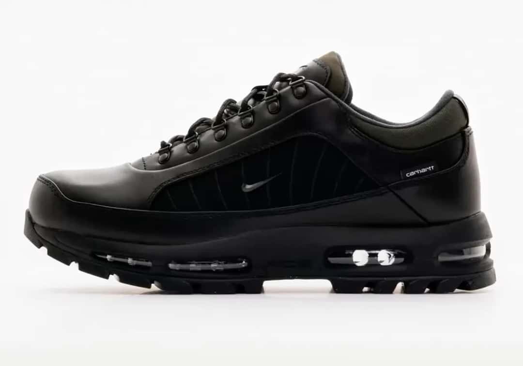 Nike Air Max Goadome Low de Carhartt WIP en negro de perfil sobre fondo blanco, con cuero negro, panel lateral negro con costuras, Swoosh metálico chico, argollas de metal y la cámara Air visible en la suela