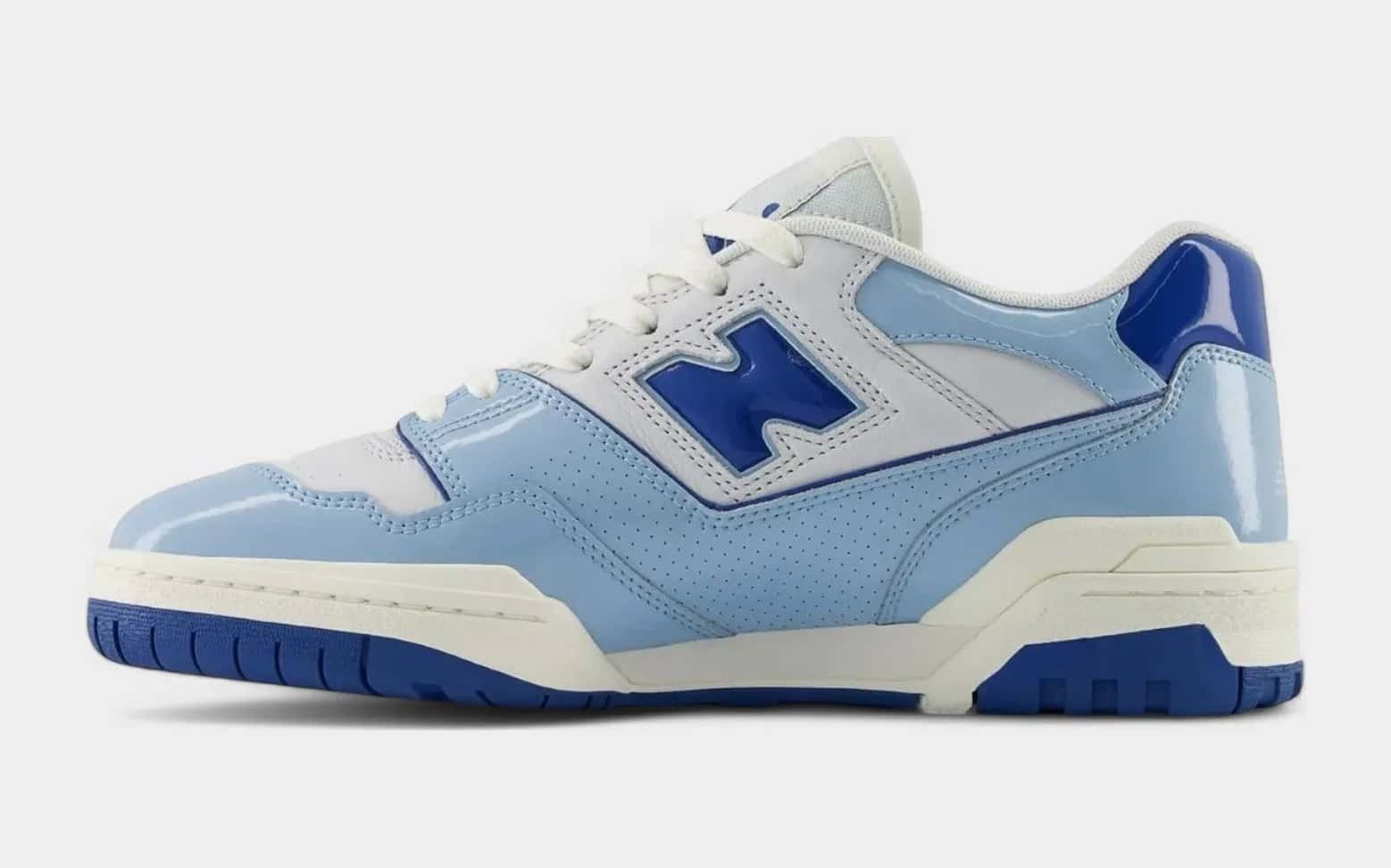 Zapatilla New Balance 550 celeste con la N y la suela azul francia, de perfil sobre fondo gris claro