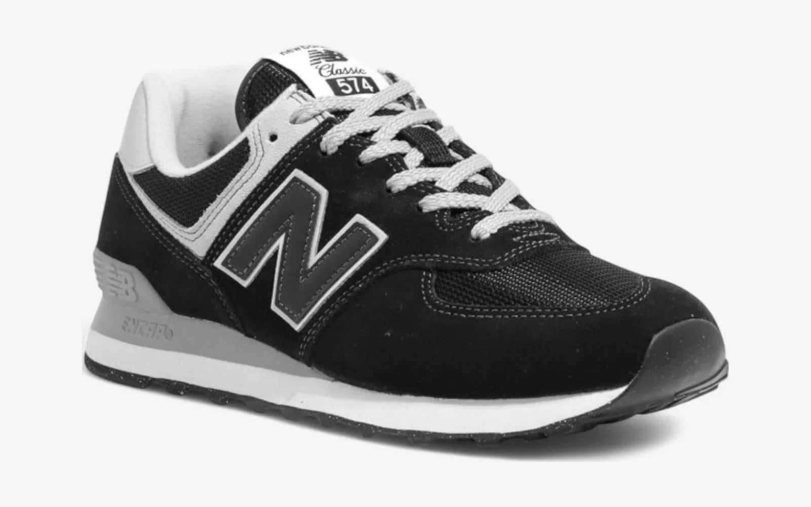 New Balance 574 negra con la N gris y la suela blanca, vista de tres cuartos sobre fondo blanco