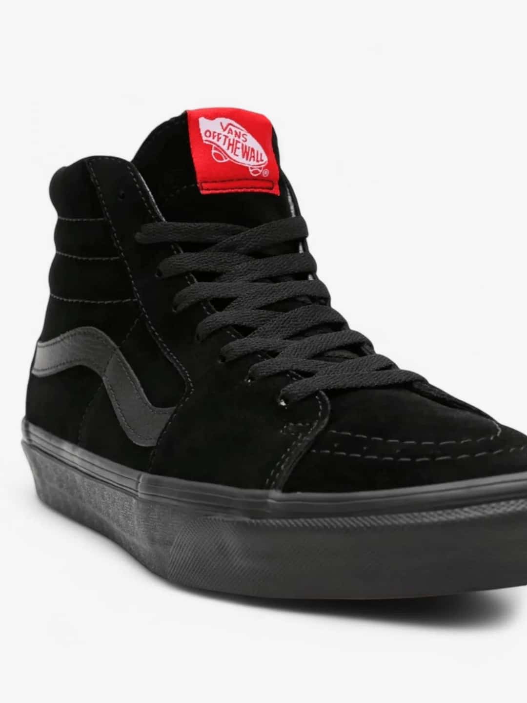 Vans Sk8-Hi negra de gamuza vista de cerca, con la franja lateral y la etiqueta roja de Vans en el talón