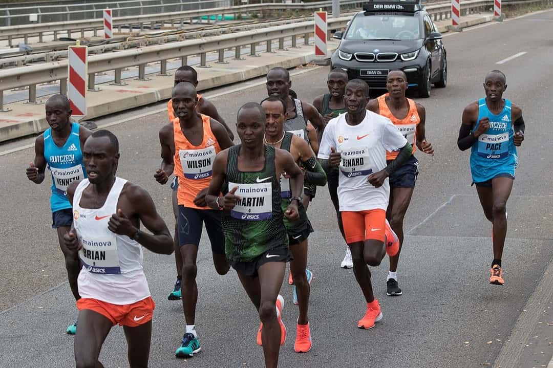 Foto de archivo: el pelotón de punta del Maratón de Frankfurt 2018, con corredores africanos de musculosas de colores, corre por una autovía con un auto de la organización atrás