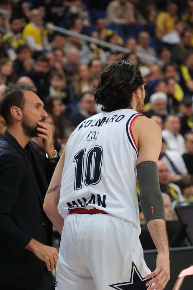 Foto de archivo: Leandro Bolmaro, de espaldas con la camiseta blanca número 10 del Olimpia Milano, junto a un hombre de traje durante un partido de Euroliga