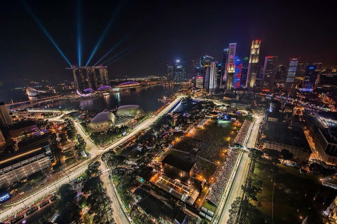 Vista aérea nocturna del circuito callejero de Marina Bay durante el Gran Premio, con las tribunas llenas, el Marina Bay Sands y los rascacielos iluminados de fondo