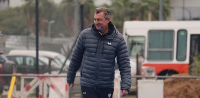 Fernando Ferrara, head coach de Las Leonas, camina con campera azul oscuro junto a una cancha de entrenamiento
