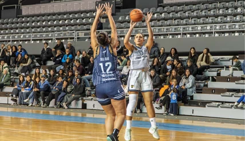 Una jugadora de Boca, con camiseta blanca y el número 13, lanza un tiro en suspensión ante la marca de Tamara Dell'Olio, de Peñarol, con la camiseta azul número 12, en el Polideportivo Islas Malvinas