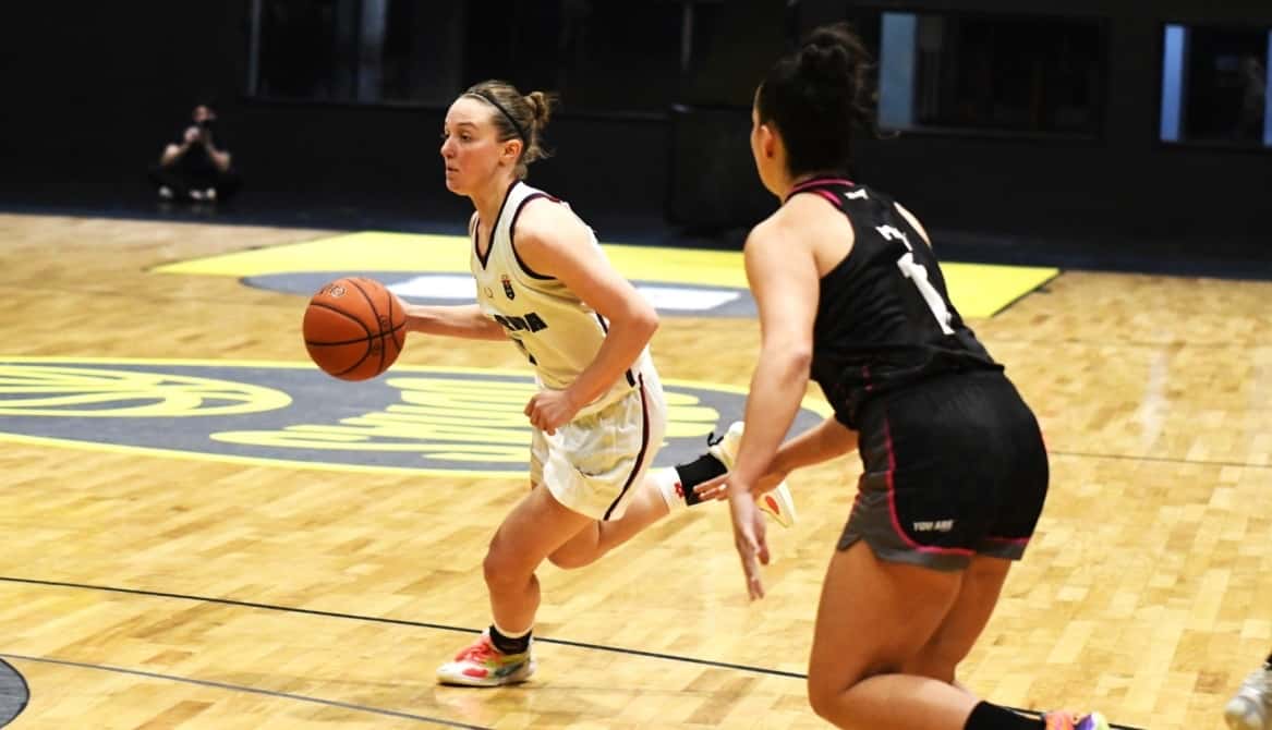Una jugadora de Unión Florida, con camiseta blanca, avanza con la pelota ante la marca de una rival de camiseta negra, en un partido de la Liga Femenina