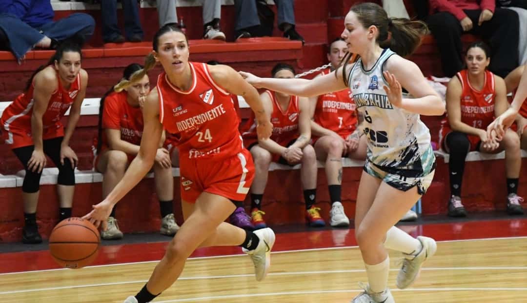 Una jugadora de Independiente de Neuquén, con camiseta roja número 24, avanza con la pelota ante la marca de una jugadora de Unión de Bahía Blanca, de blanco