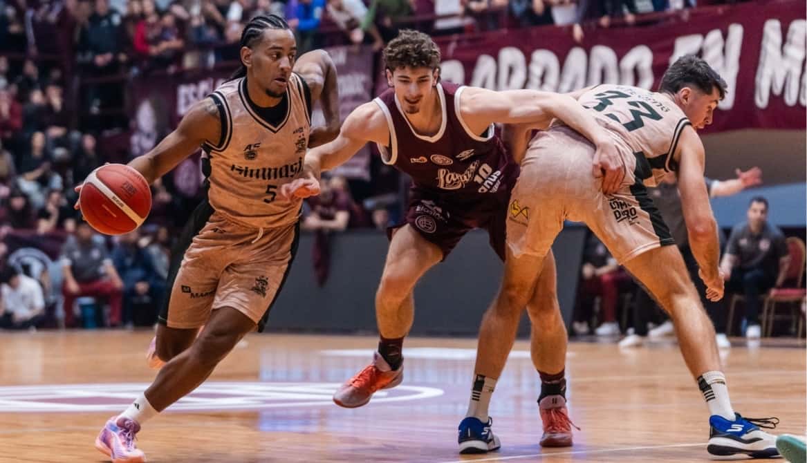 Un jugador de Gimnasia de Comodoro avanza con la pelota ante la marca de dos jugadores de Lanús en el partido inaugural de la Liga Nacional