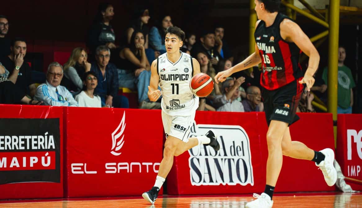 Ramiro Frontera, con la camiseta blanca número 11 de Olímpico de La Banda, avanza con la pelota seguido por un jugador de San Martín, de rojo y negro, en el Raúl Argento Ortiz