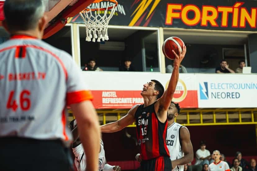 Lautaro Berra, con la camiseta roja y negra número 15 de San Martín, sube a encestar ante la marca de Olímpico en el Raúl Argento Ortiz