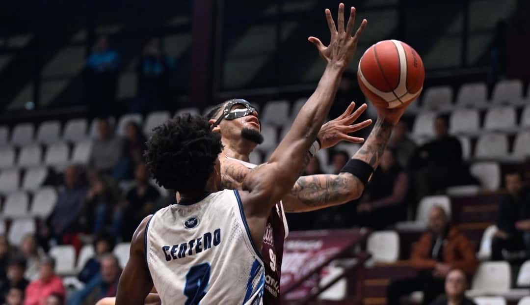 Un jugador de Regatas, de blanco con el número 9, pelea la pelota en el aire con un jugador de Lanús, de granate, en el Rotili