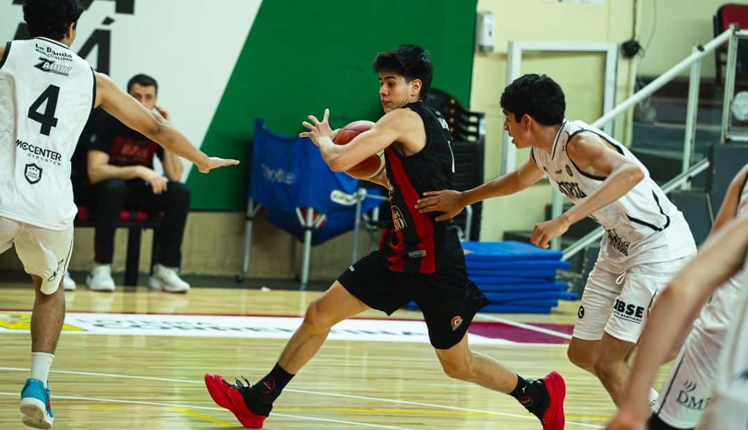 Un jugador de San Martín, con camiseta negra y roja, avanza con la pelota entre dos rivales de Olímpico de La Banda, de blanco