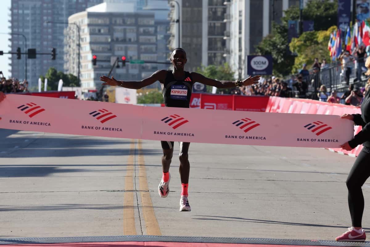 Amos Kipruto abre los brazos al cortar la cinta de llegada del Maratón de Chicago 2026, con edificios del centro de Chicago de fondo