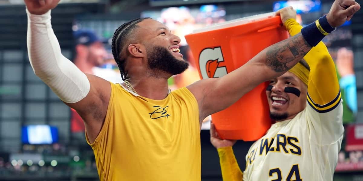 Jackson Chourio, con remera amarilla de los Brewers, festeja con los brazos en alto mientras William Contreras, con la camiseta número 24, se acerca por detrás con un balde naranja