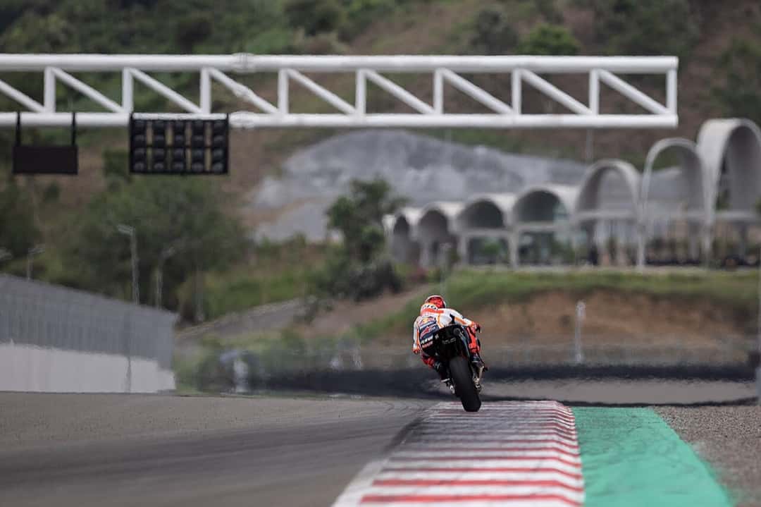 Foto de archivo: un piloto con la moto naranja y blanca encara la recta principal de Mandalika, con el semáforo de largada y las tribunas de techos curvos de fondo