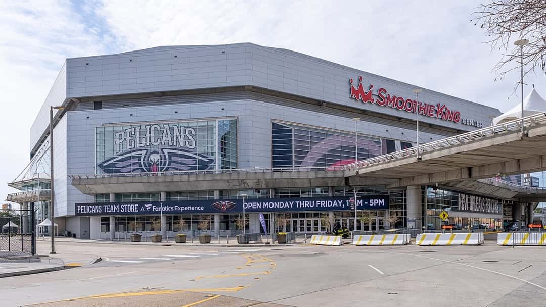 Imagen del estadio: el frente del Smoothie King Center de Nueva Orleans, con el logo de los Pelicans en la fachada y la explanada vacía adelante